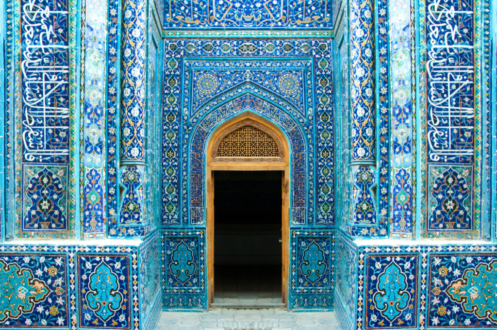 Symmetrical, richly decorated with blue ceramic islamic tiles, entrance and open door in Shah-I-Zinda